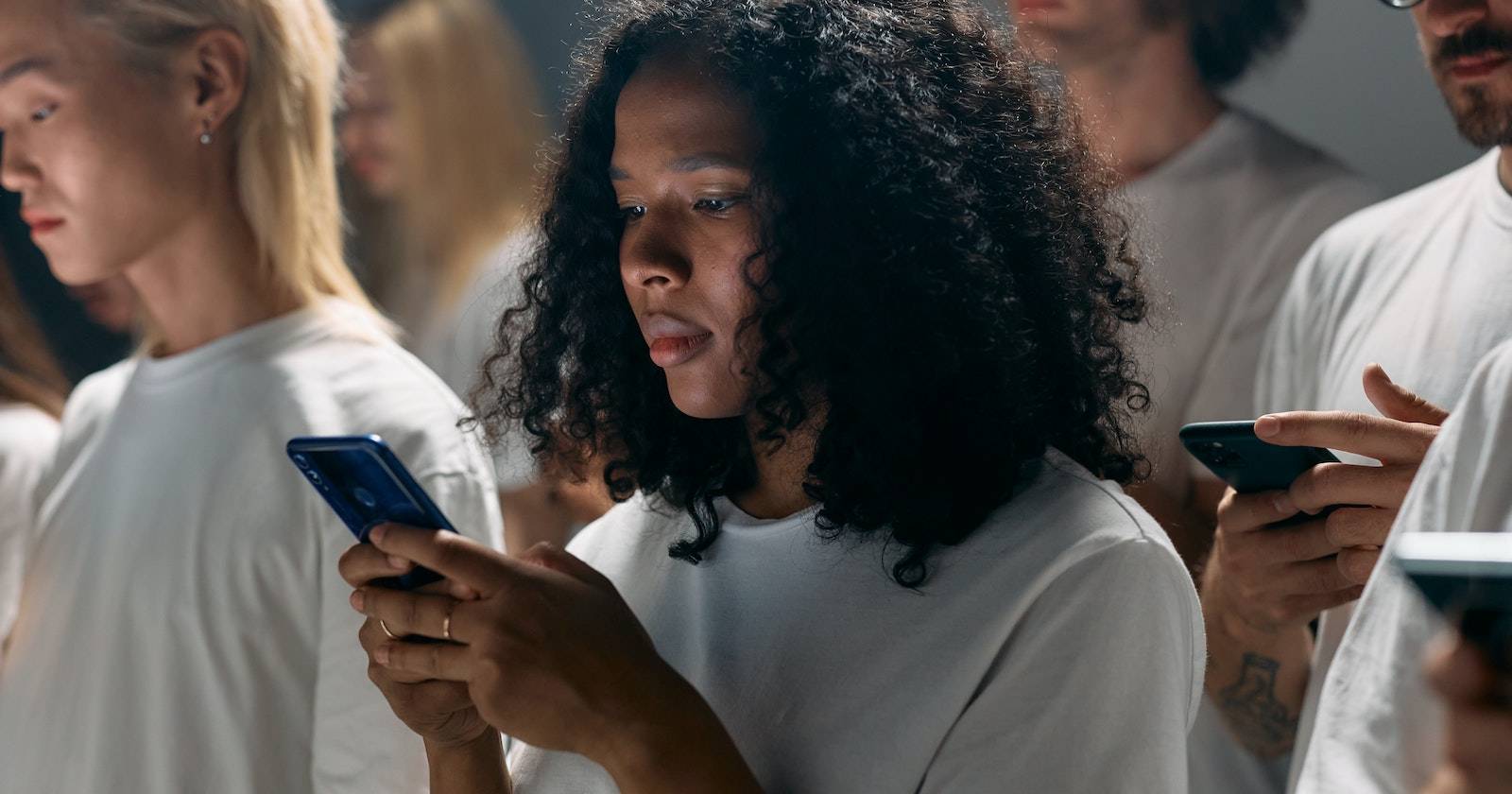 группа людей в белой одежде, смотрящих в смартфоны