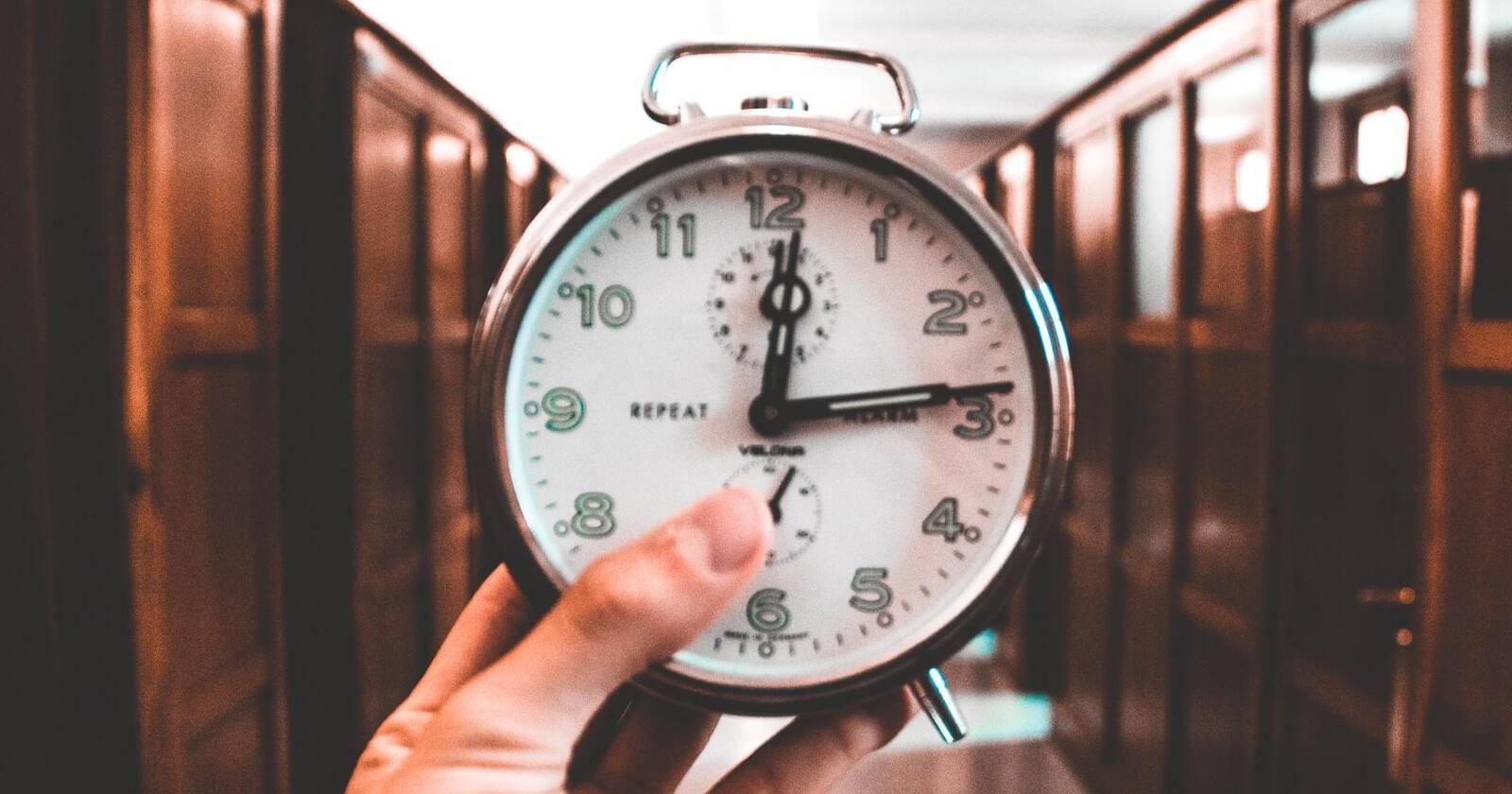 Человек держит будильник