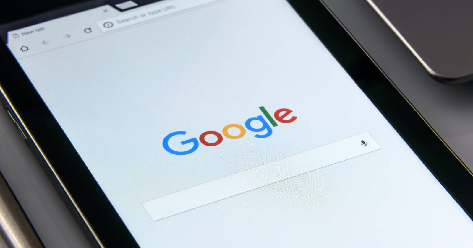 Сайт Google отображается на телефоне, лежащем на столе.