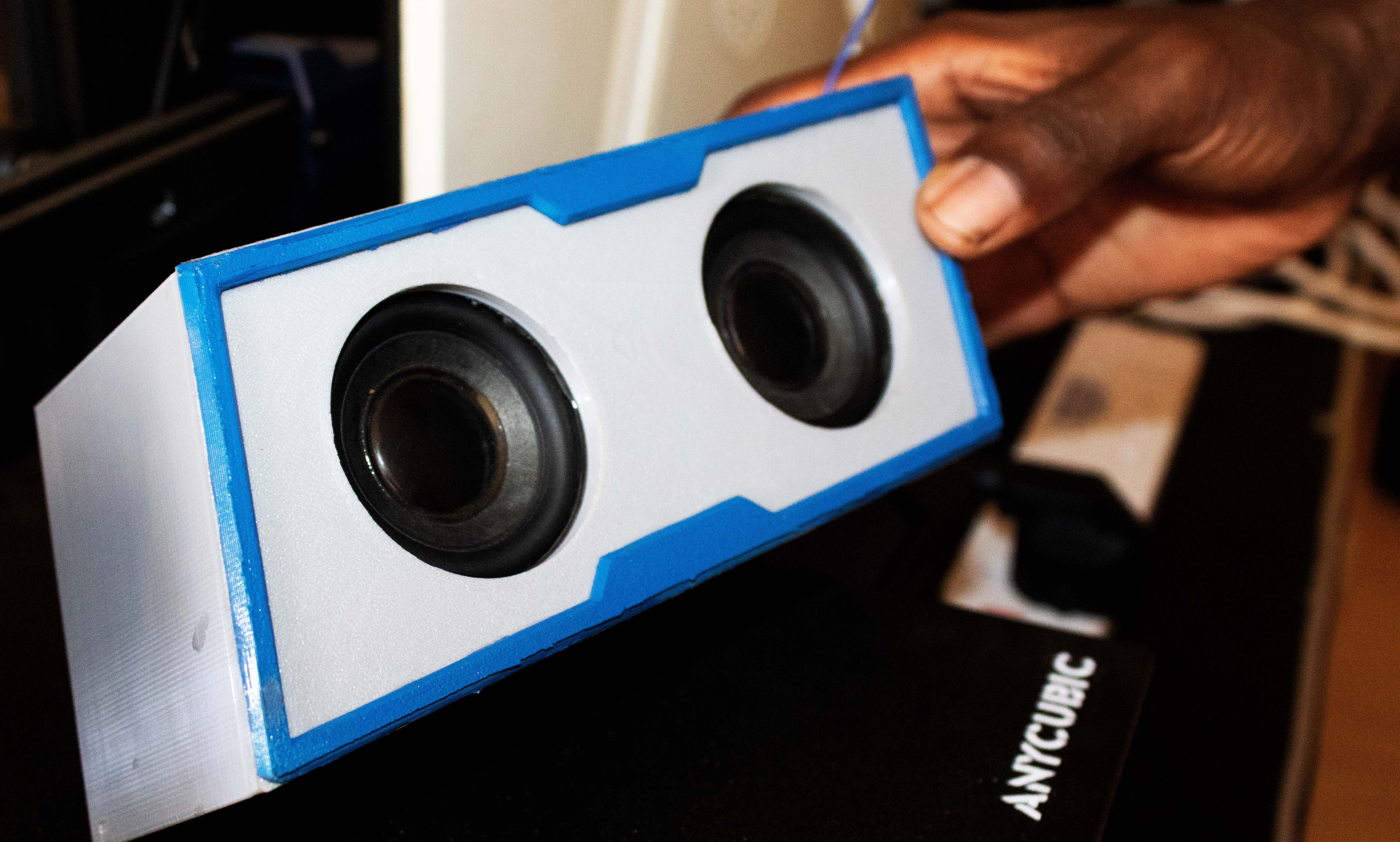 Готовый белый Bluetooth-динамик с синей полосой в руке