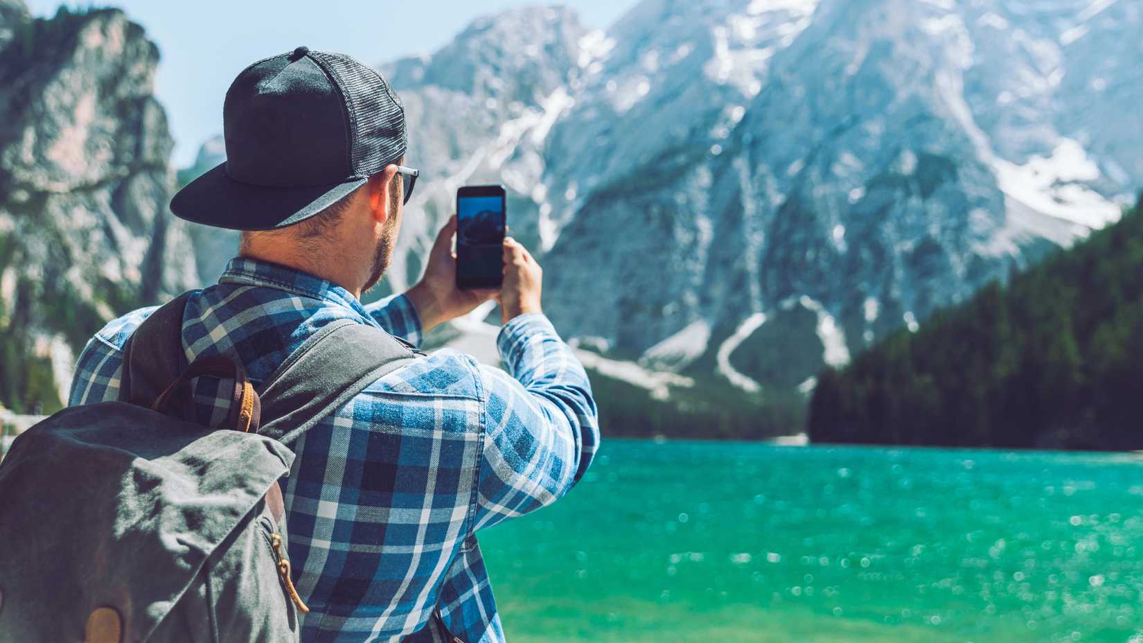 мужчина фотографирует горы на телефон