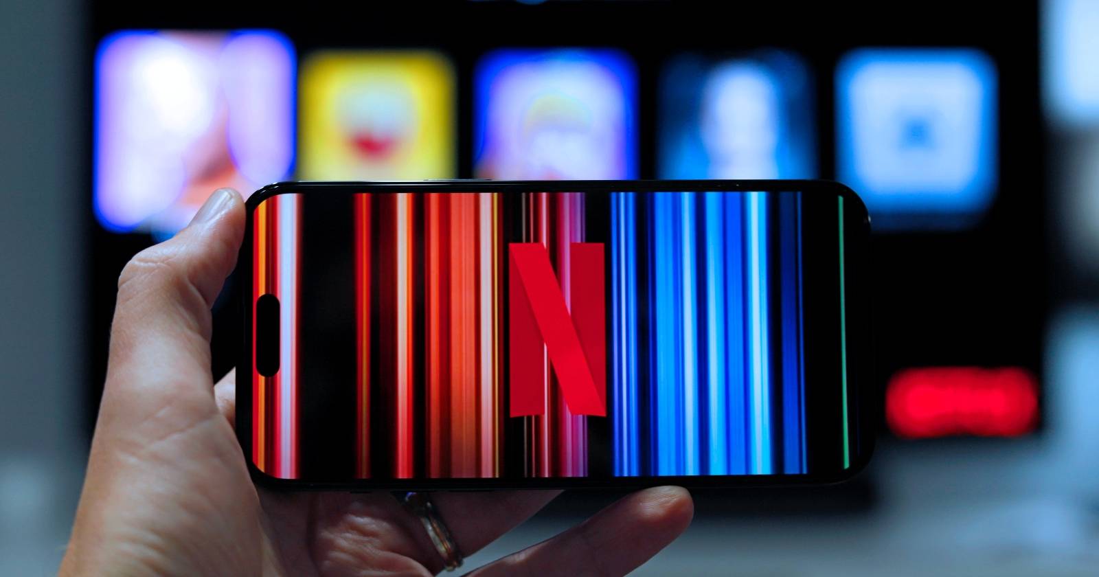 Рука держит смартфон с логотипом Netflix на экране