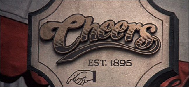 Люди в баре смотрят матч на большом экране, смеются и аплодируют