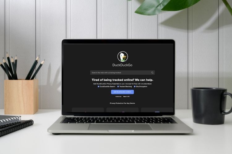 MacBook Pro на белом столе, окно DuckDuckGo в браузере