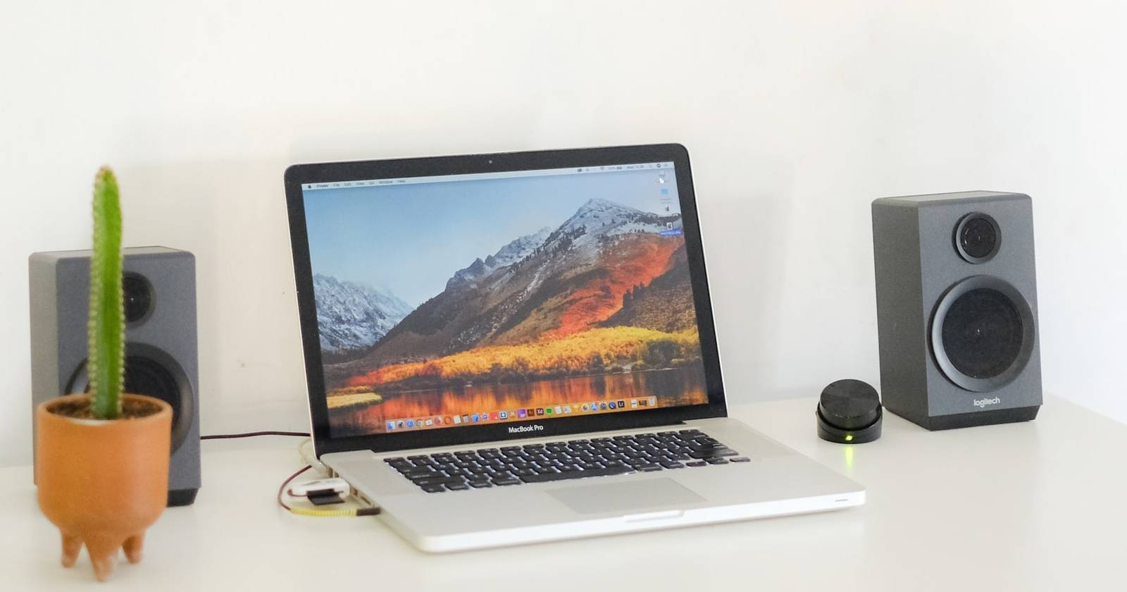 MacBook на столе с колонками и кактусом