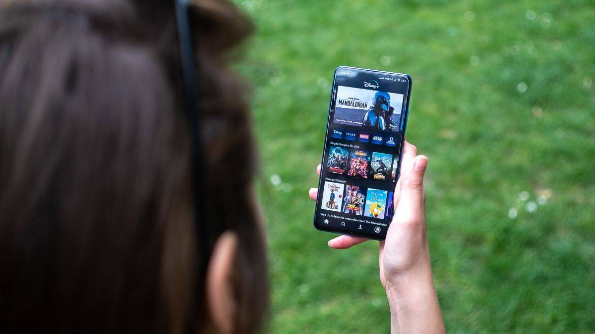 Женщина смотрит Disney Plus на телефоне