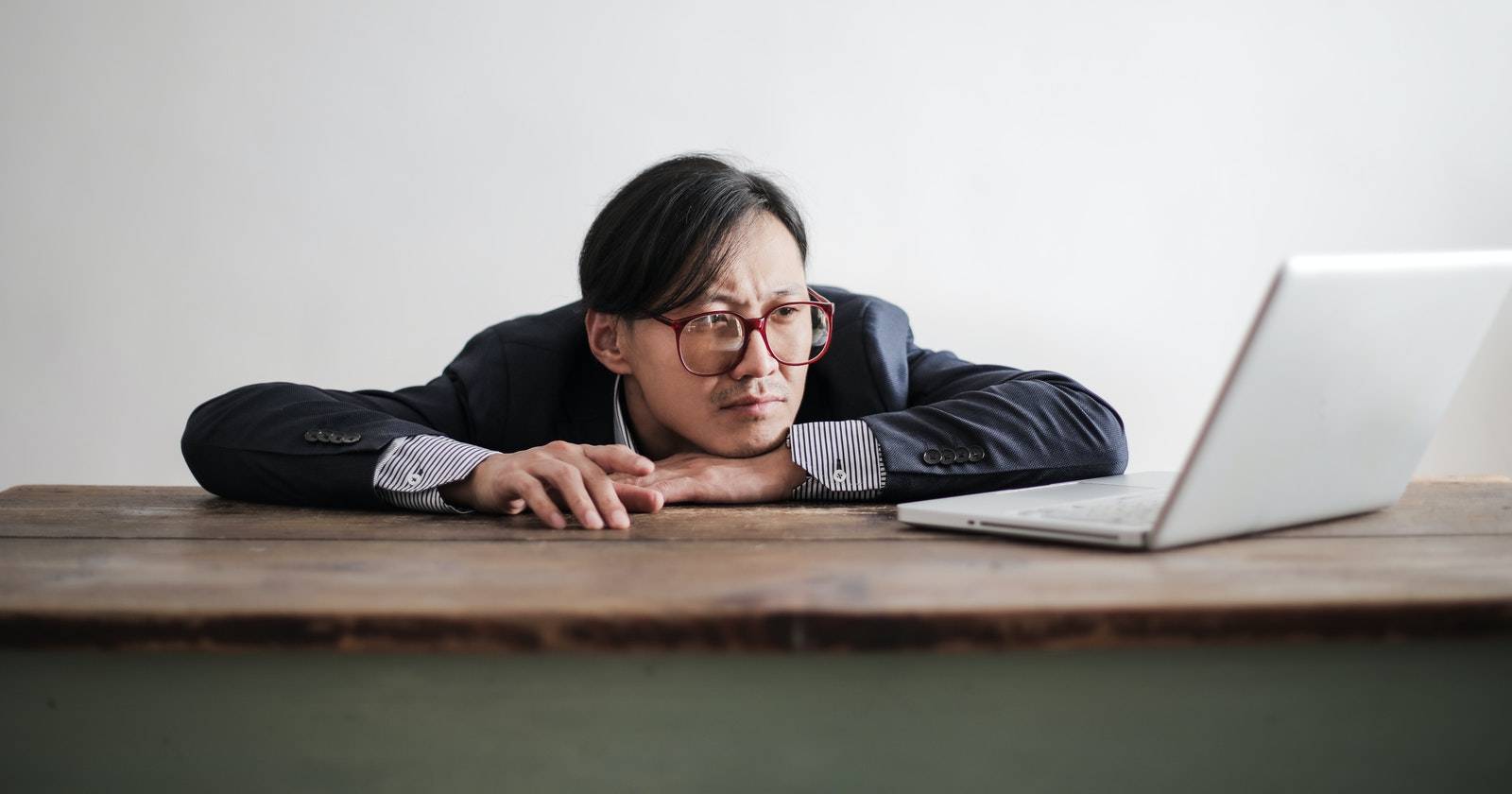 Ленивый мужчина с скучающим лицом смотрит в ноутбук