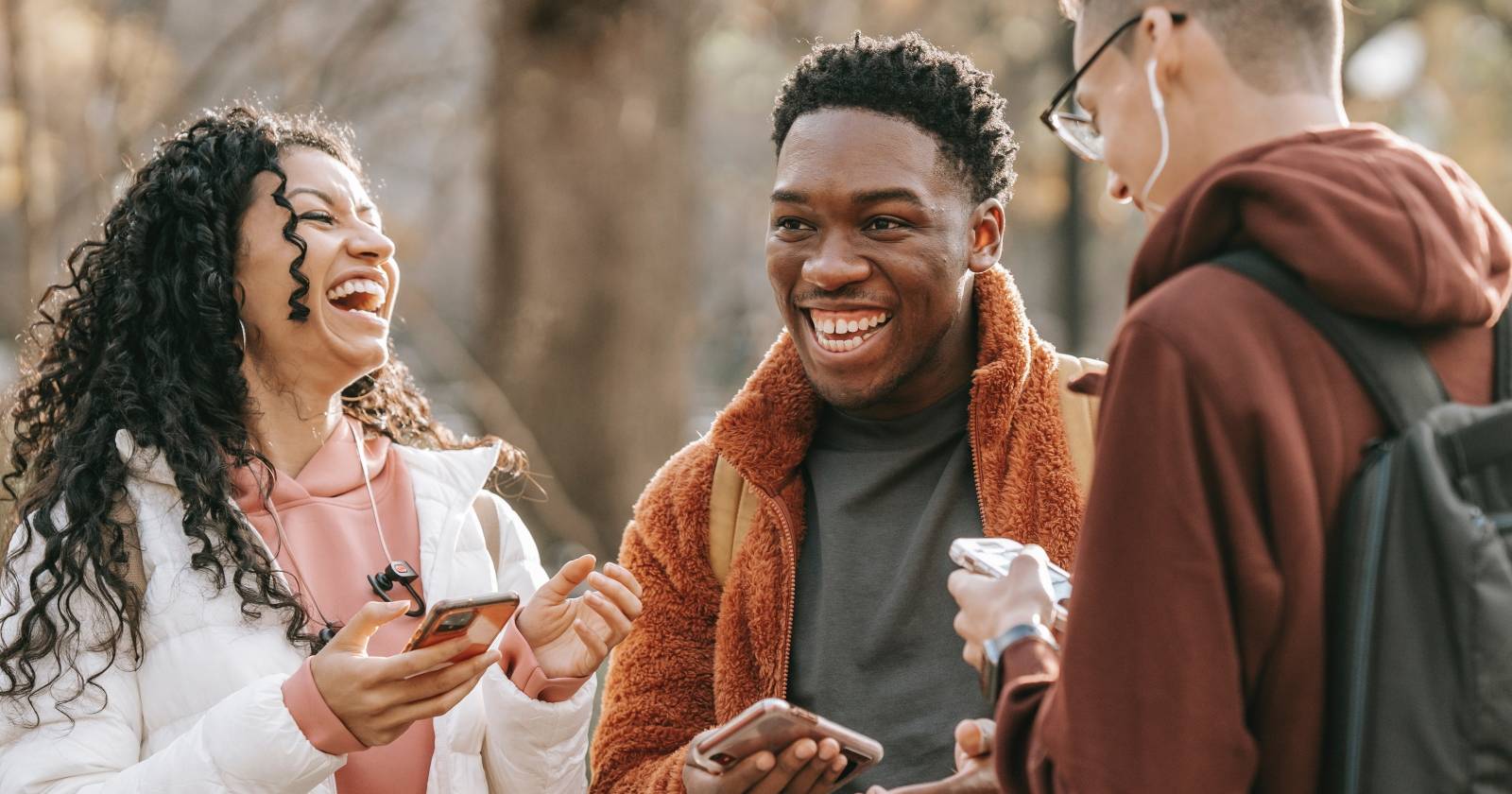 Группа людей с телефонами смеются на улице