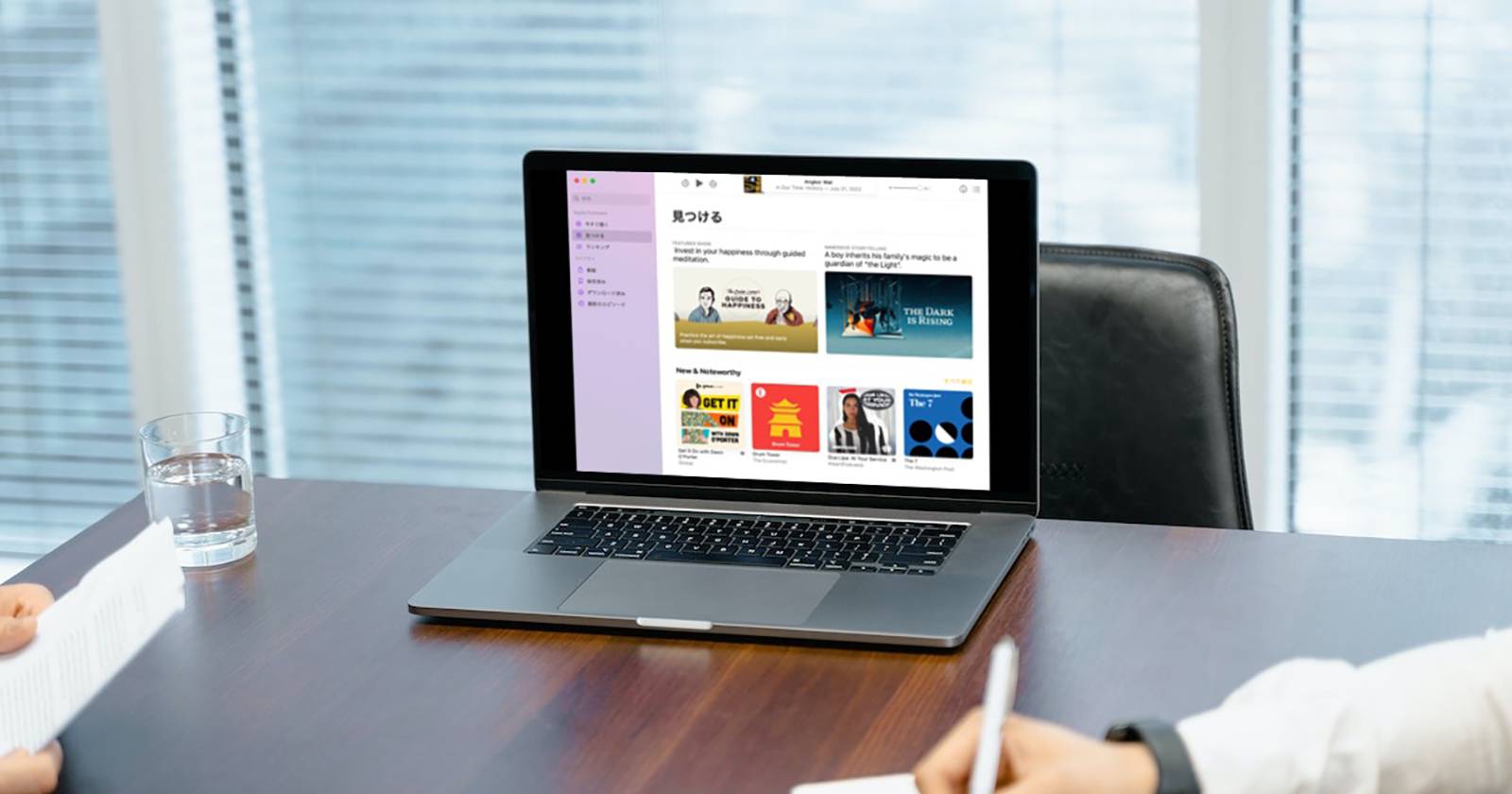 Приложение Подкасты на MacBook на деревянном столе, интерфейс на японском