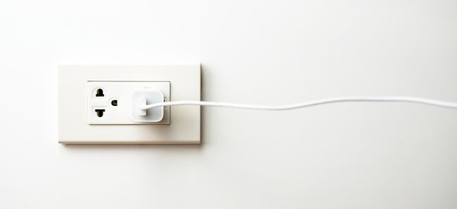 Настенный зарядный адаптер и кабель рядом с телефоном