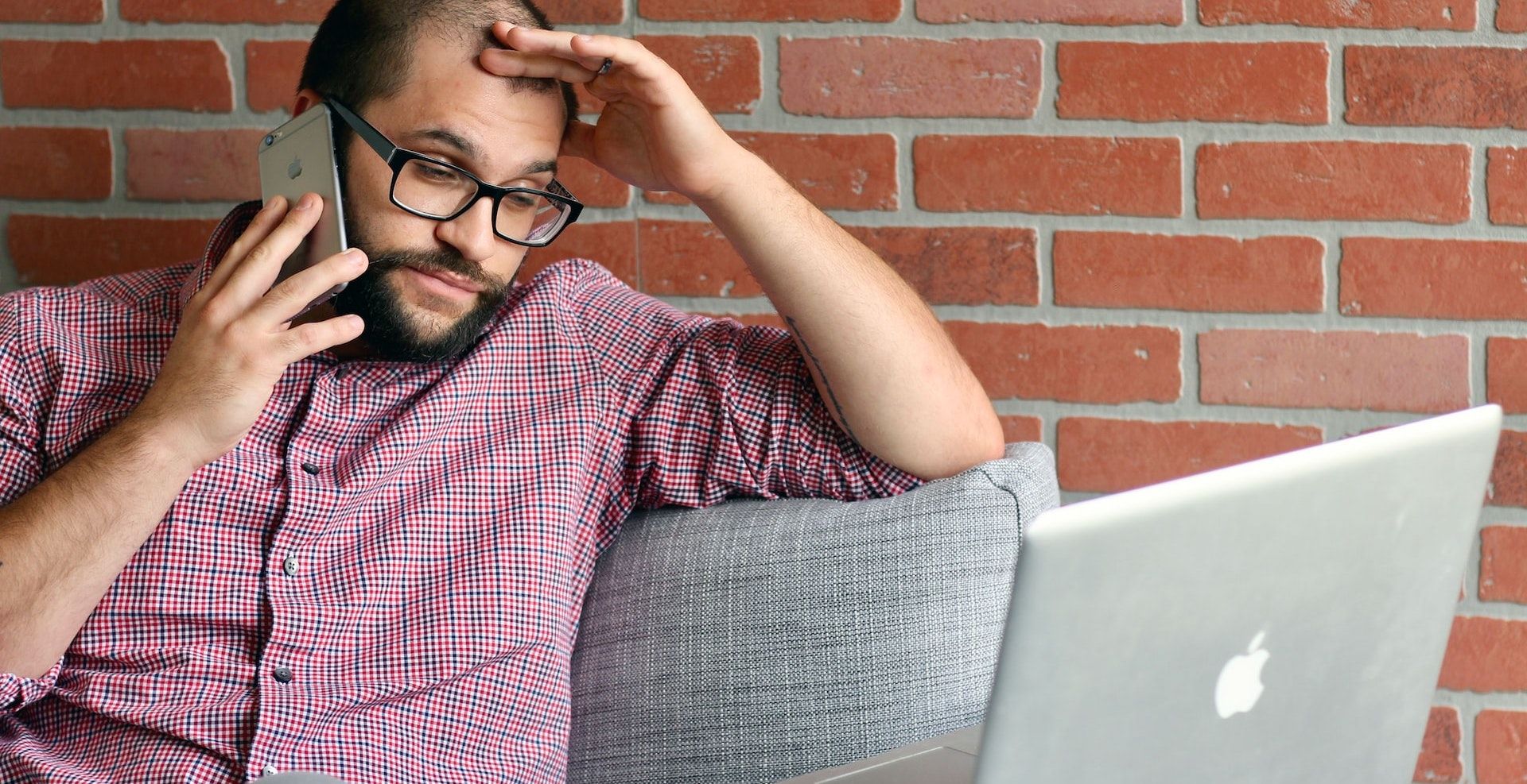 Мужчина звонит по телефону и работает за ноутбуком