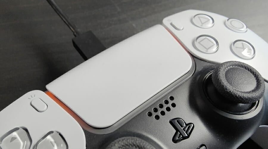 Контроллер PS5 заряжается от кабеля USB-C на белом фоне