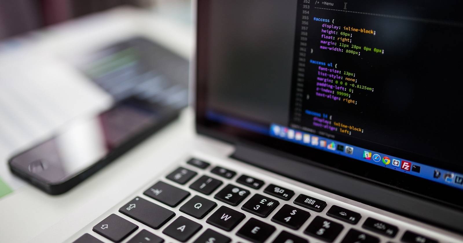 Код на экране ПК, рядом на столе — смартфон