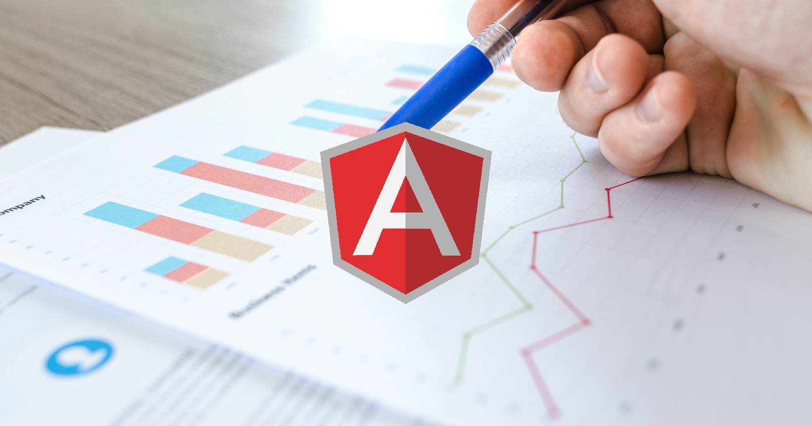 Логотип Angular на фоне руки с ручкой и бумаги с диаграммами и графиками