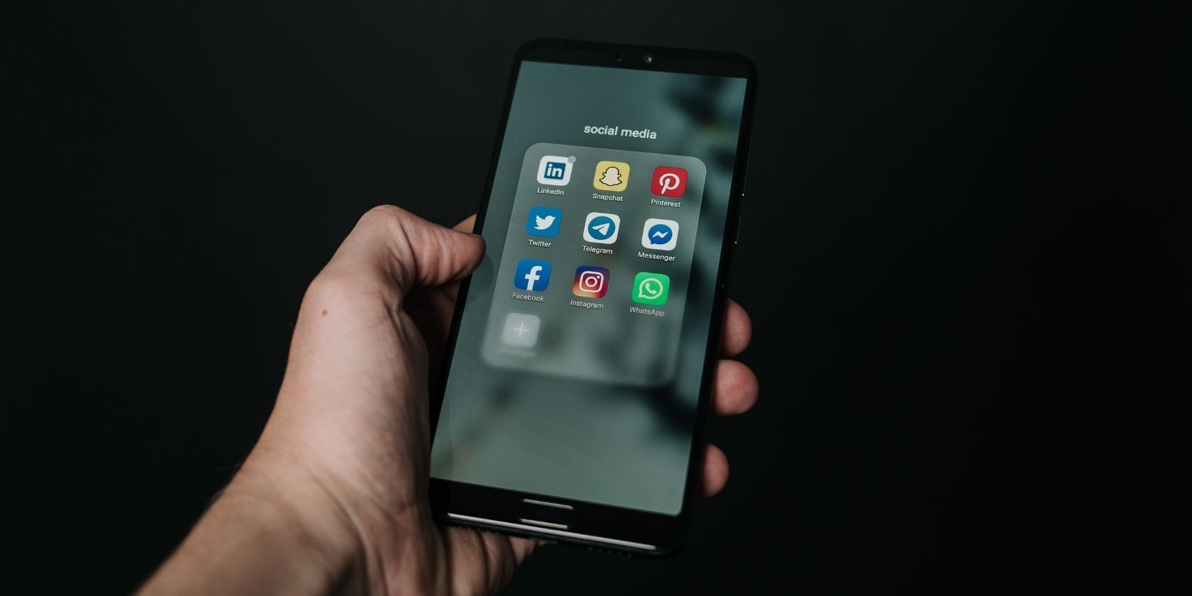 person holding smartphone with social media app menu open