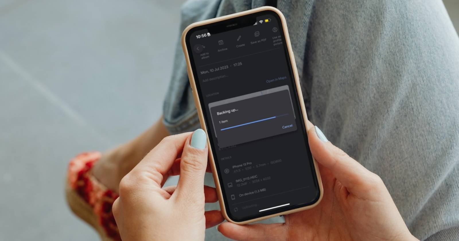 Крупный план рук, держащих iPhone с экраном процесса загрузки фотографии