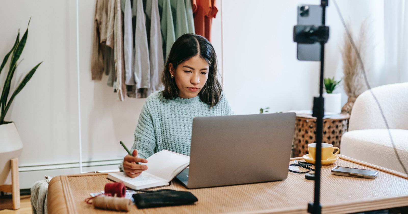 Женщина пишет за столом с ноутбуком перед собой